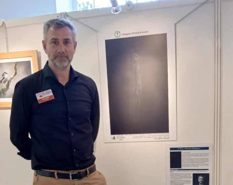 Stefan Gerrits, winner of the 1st Prize in the 'Bird Portrait' category, stands proudly in front of his exhibited photograph.
